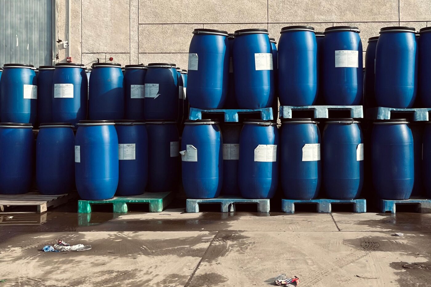 Modré sudy s chemikáliemi naskládané na paletách u skladu