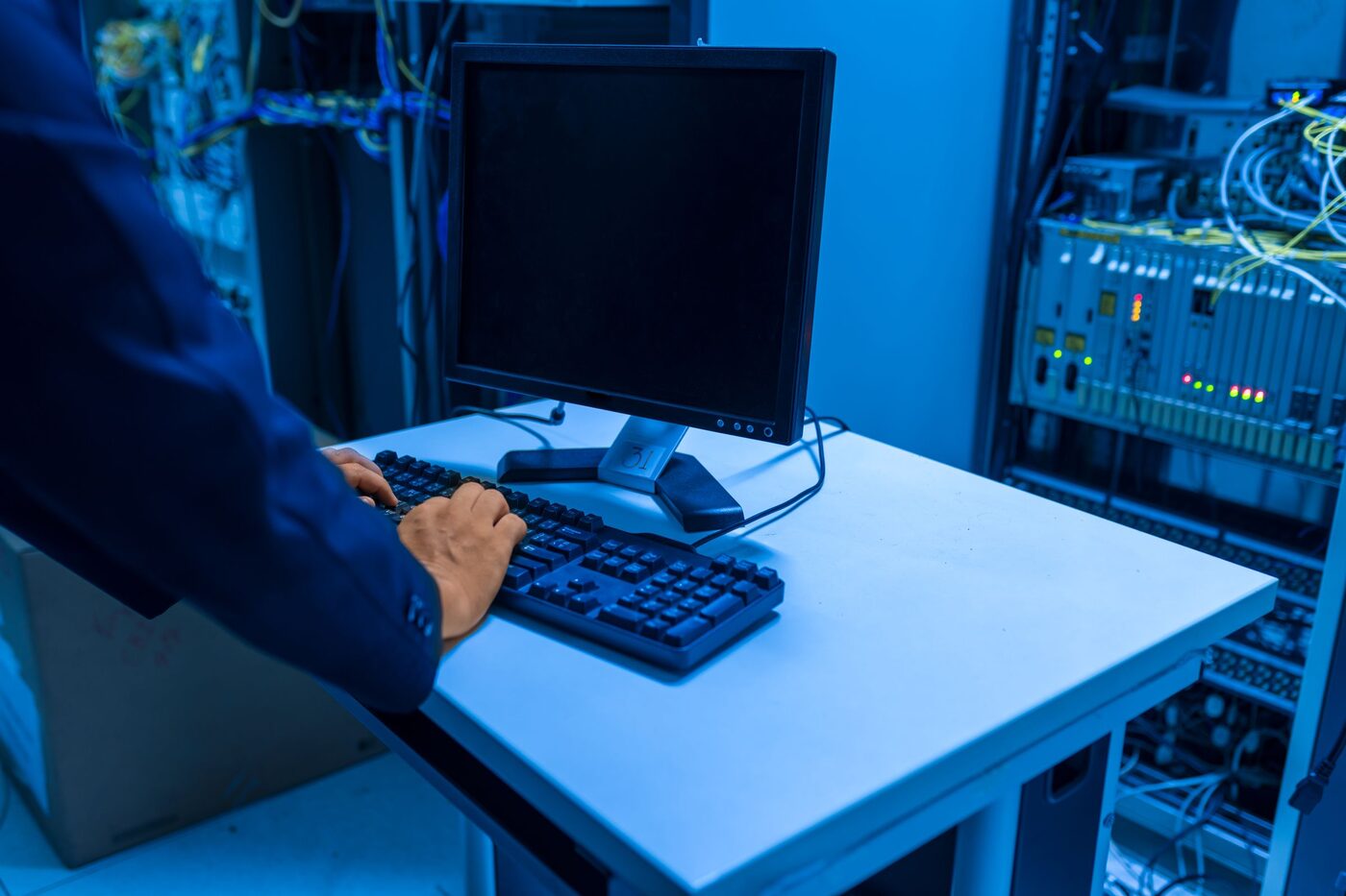 Technik u konzole v serverovně mezi rozvaděči