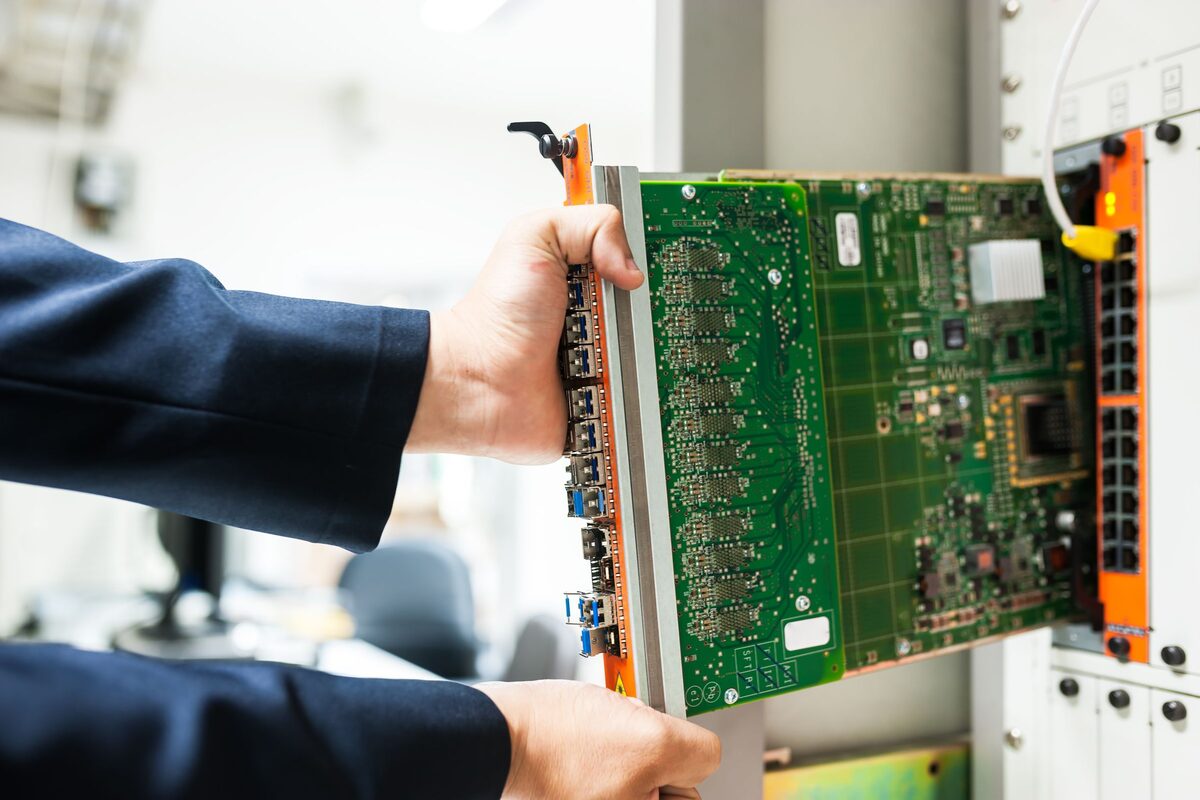 Technik zasouvá kartu do rozvaděče se síťovými prvky