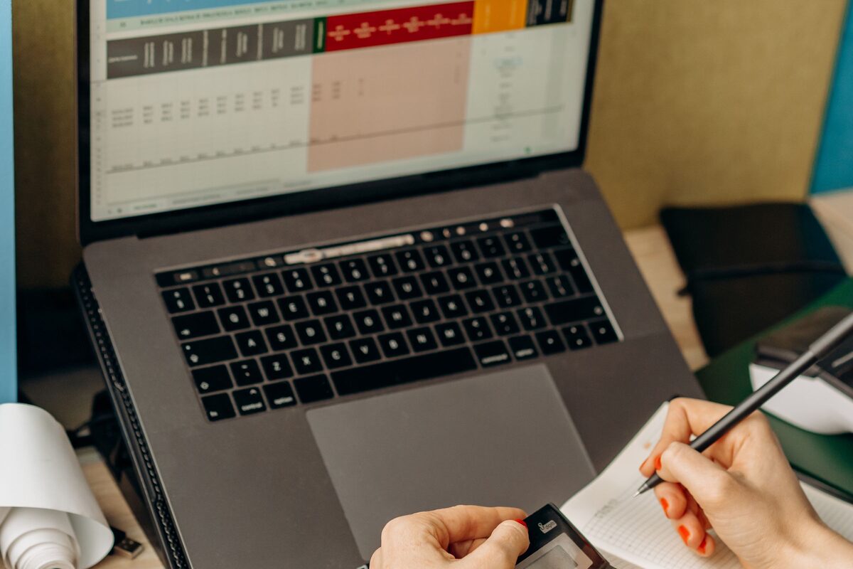 Notebook s tabulkou dat, vedle ruce zapisují poznámky